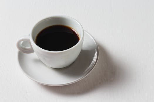 A single coffee cup with a dark brew on a bright white surface.