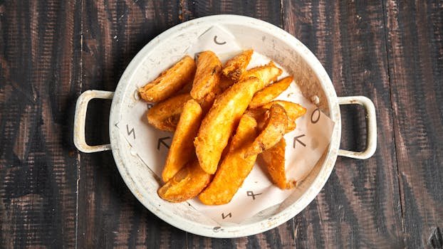 Golden crispy potato wedges served in a rustic white bowl on wood.