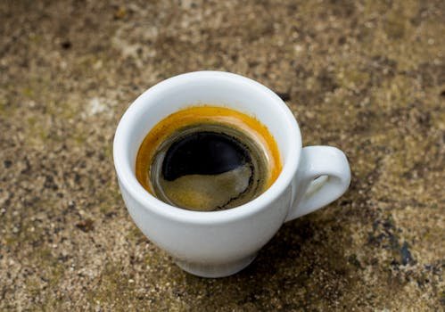 Close-up of a rich espresso served in a classic white cup on a textured surface.